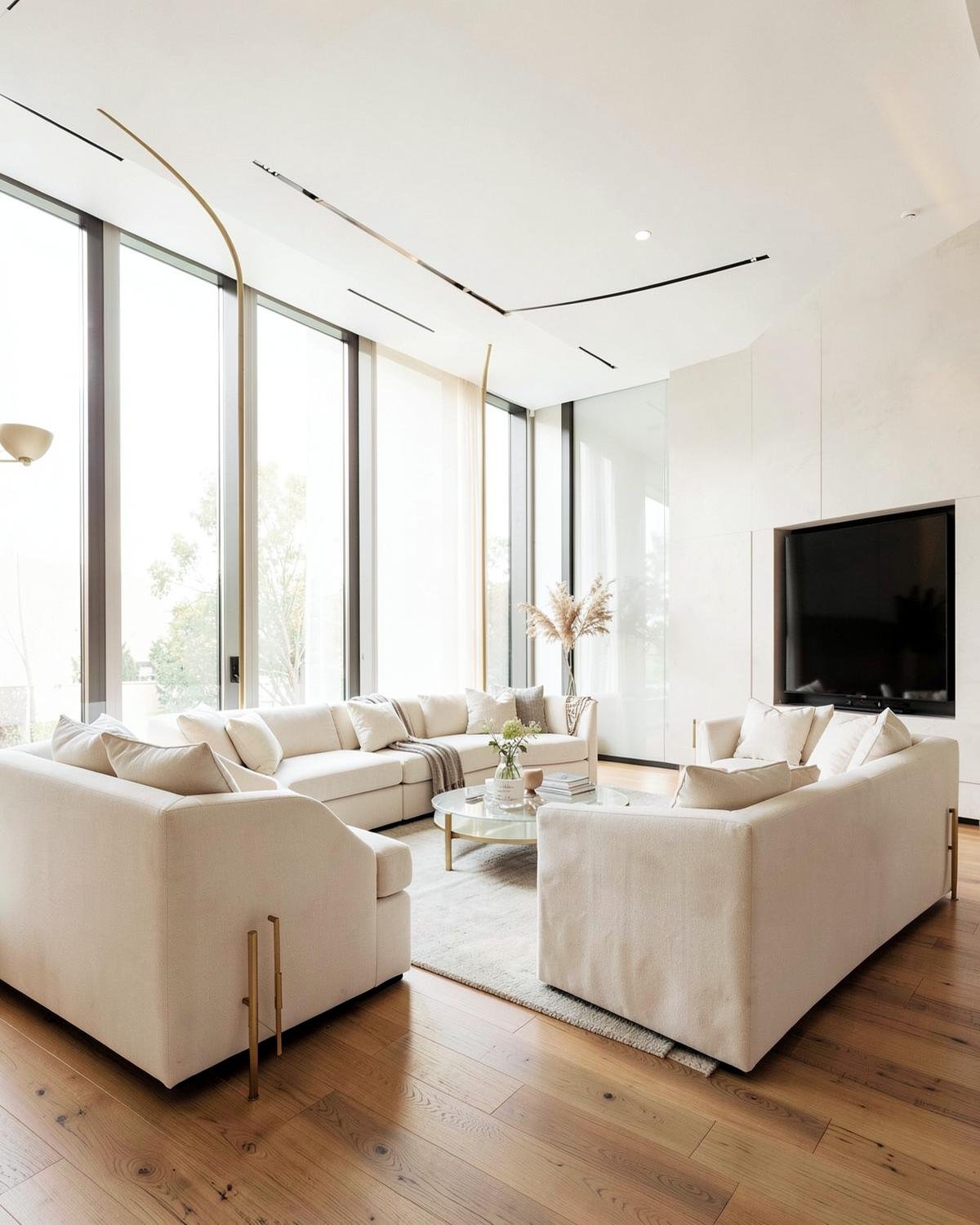 Bright luxury living room with ivory sofas, oak floors and full-height windows